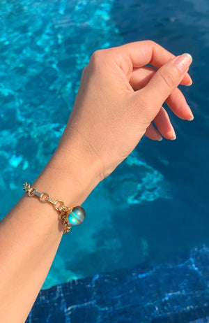 PLECAS Voda bracelet on wrist over swimming pool water.