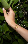 Hand touching leaves wearing Plecas Jewelry Rising Sun Bracelet